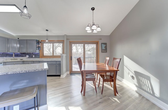 dining room with light wood-style floors, vaulted ceiling, and baseboards