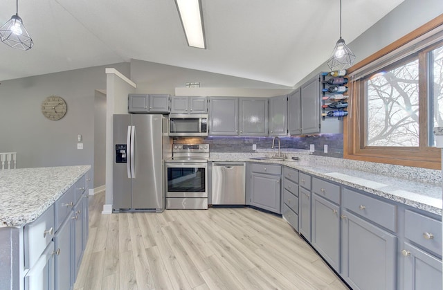 kitchen with light wood-style flooring, vaulted ceiling, stainless steel appliances, gray cabinetry, and a sink