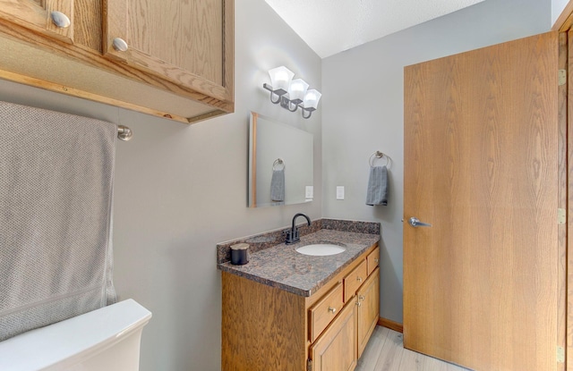 half bath featuring vanity, toilet, and wood finished floors