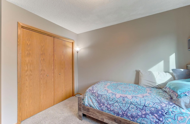 carpeted bedroom with a textured ceiling and a closet