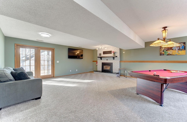 playroom with billiards, baseboards, a textured ceiling, carpet flooring, and a brick fireplace