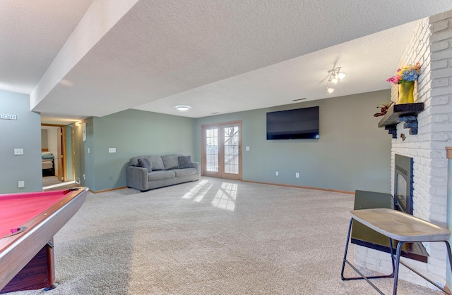 playroom featuring carpet floors, a fireplace, a textured ceiling, and baseboards