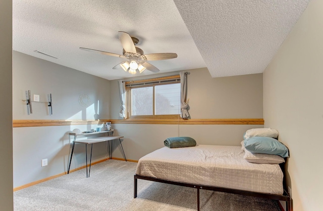 carpeted bedroom featuring visible vents, a textured ceiling, baseboards, and a ceiling fan