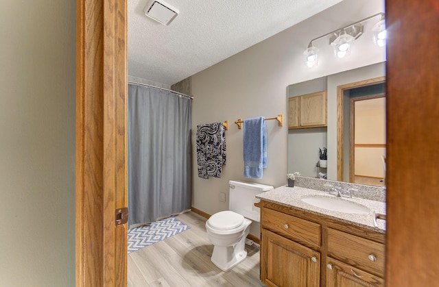 full bath featuring toilet, wood finished floors, curtained shower, a textured ceiling, and vanity