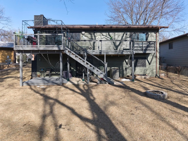 rear view of house featuring a fire pit, stairway, fence, a wooden deck, and central AC