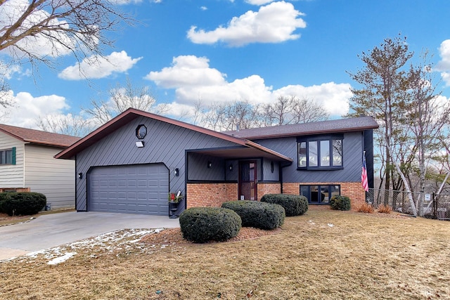 tri-level home featuring brick siding, a front yard, fence, a garage, and driveway