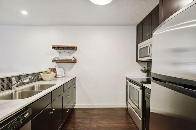 kitchen featuring stainless steel appliances, dark wood-type flooring, a sink, light countertops, and decorative backsplash