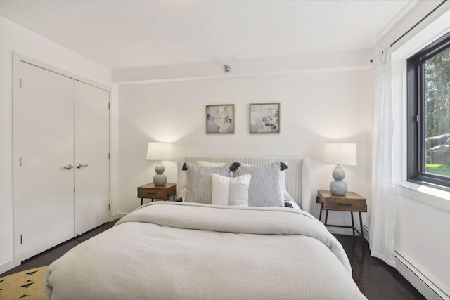 bedroom featuring a baseboard radiator, a closet, and wood finished floors