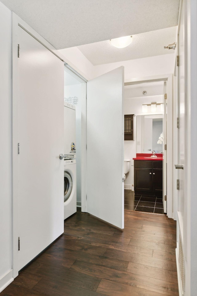 laundry room featuring washer / clothes dryer, a sink, a textured ceiling, wood finished floors, and laundry area