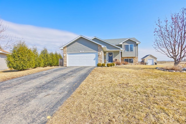 tri-level home with driveway, stone siding, an attached garage, and a front lawn