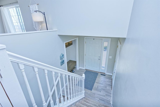 foyer entrance with baseboards, visible vents, stairway, and wood finished floors