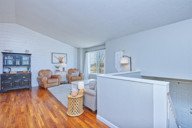 living area featuring dark wood-style floors, a textured ceiling, and lofted ceiling