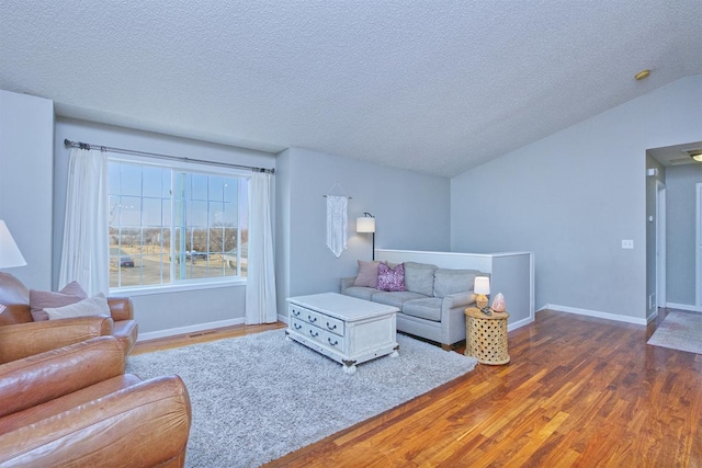 living area featuring lofted ceiling, a textured ceiling, baseboards, and wood finished floors