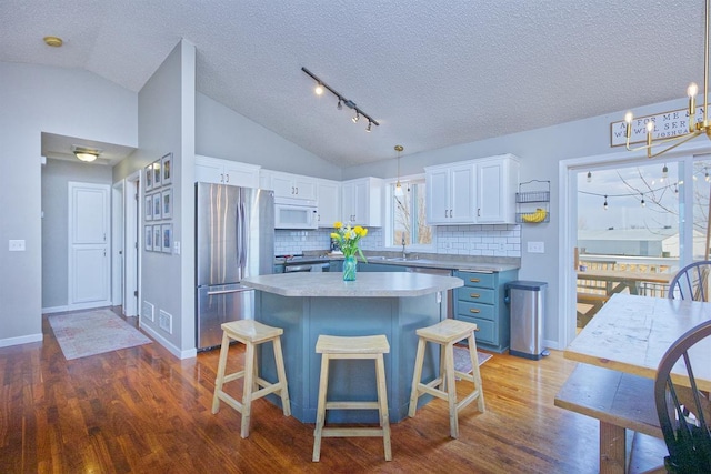 kitchen featuring freestanding refrigerator, vaulted ceiling, a sink, and white microwave