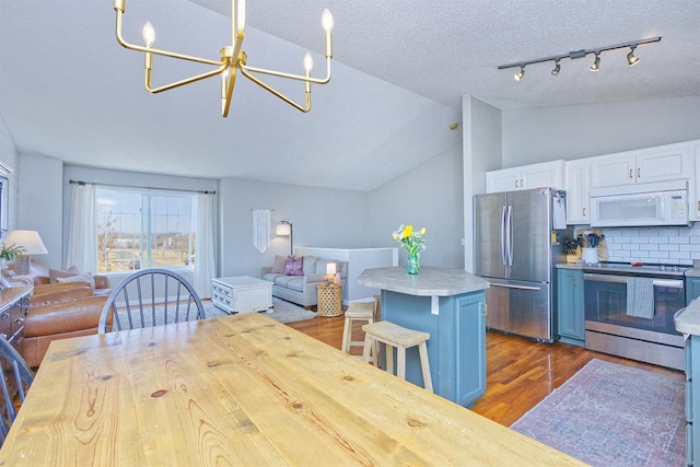 kitchen featuring dark wood-style flooring, stainless steel appliances, open floor plan, white cabinets, and a chandelier