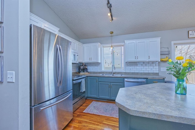 kitchen featuring wood finished floors, appliances with stainless steel finishes, a sink, and white cabinets