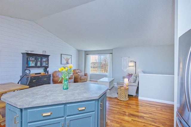 kitchen featuring light wood-style floors, vaulted ceiling, open floor plan, and light countertops