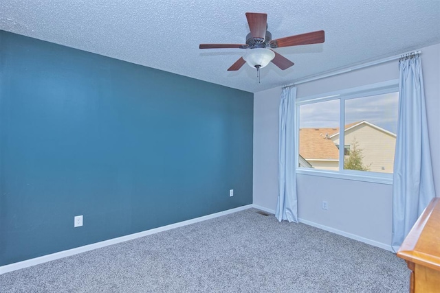 unfurnished room featuring a textured ceiling, carpet flooring, a ceiling fan, and baseboards