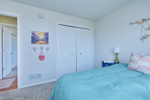 carpeted bedroom with a textured ceiling, a closet, visible vents, and baseboards