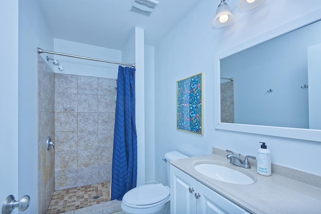 full bathroom featuring visible vents, a tile shower, vanity, and toilet