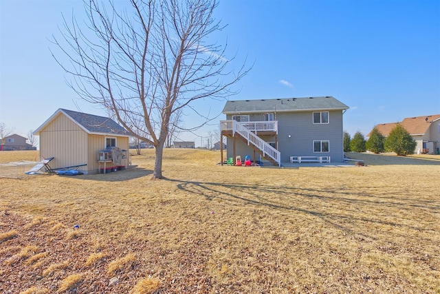 rear view of property with stairs, a yard, and an outbuilding