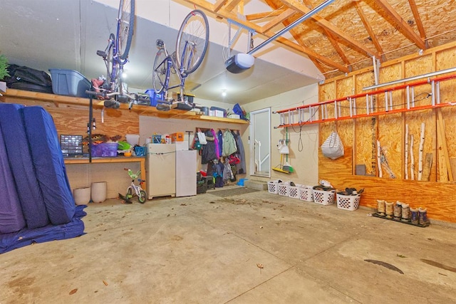 garage with a garage door opener and freestanding refrigerator