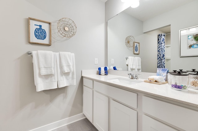 bathroom featuring a shower with curtain, vanity, and baseboards