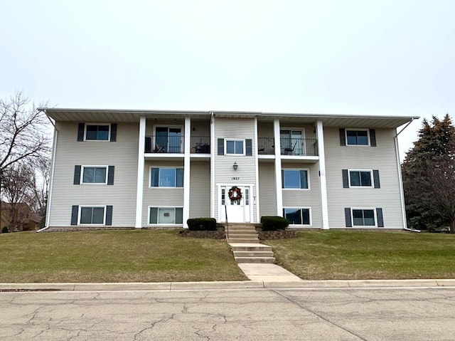 view of front of house featuring a balcony and a front lawn