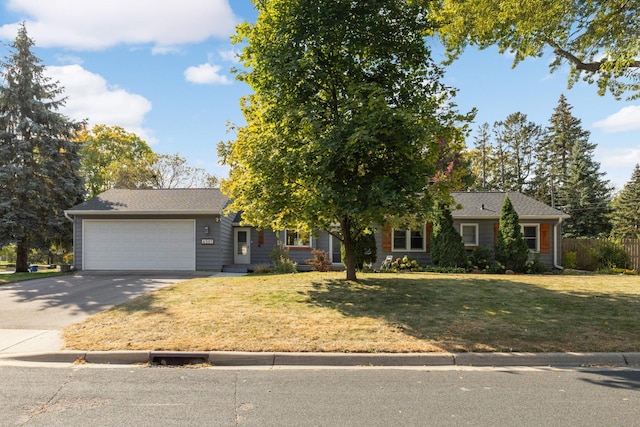 view of front of house featuring a garage, driveway, fence, and a front lawn