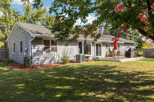 rear view of property featuring cooling unit, fence, a yard, a wooden deck, and a chimney