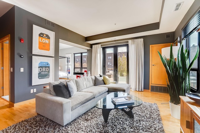 living room featuring visible vents, light wood-style floors, and french doors