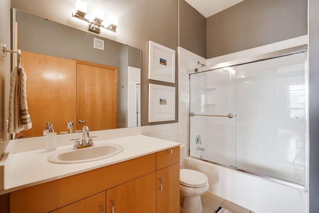 full bathroom featuring tile patterned flooring, toilet, vanity, and bath / shower combo with glass door