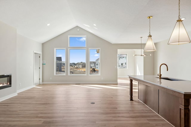 unfurnished living room with a sink, baseboards, and light wood-style floors