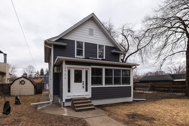 view of front of property with entry steps, a storage unit, fence, and an outbuilding