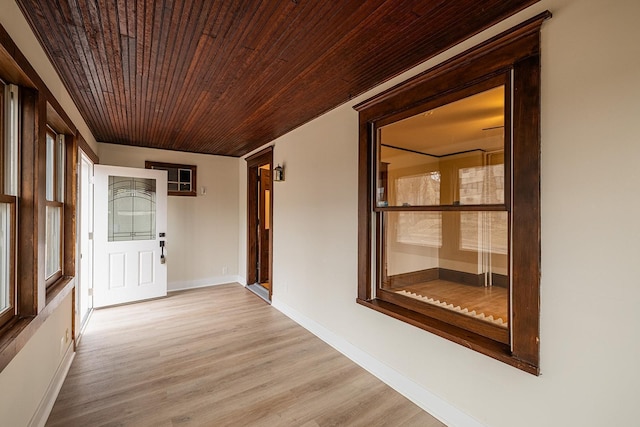 hallway featuring light wood-style floors, wood ceiling, and baseboards