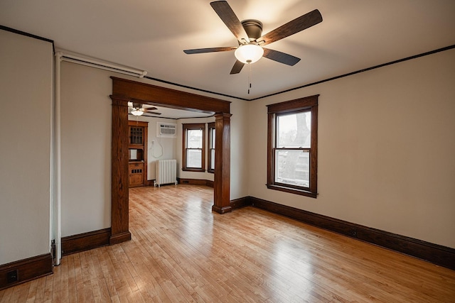 empty room with light wood-style floors, radiator heating unit, baseboards, and crown molding