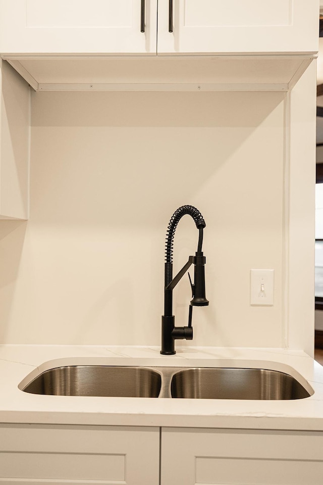 room details with light countertops, a sink, and white cabinetry