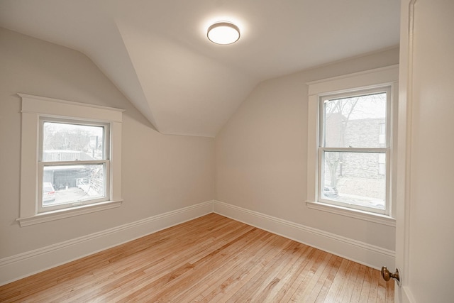 bonus room featuring lofted ceiling, plenty of natural light, light wood-style flooring, and baseboards