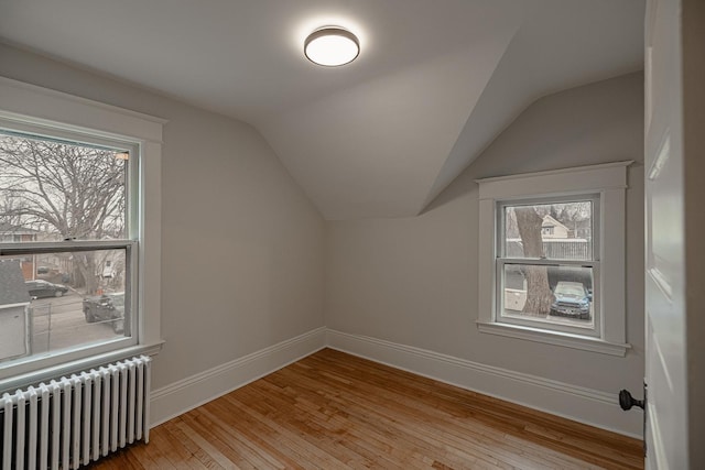 additional living space featuring baseboards, vaulted ceiling, radiator heating unit, and hardwood / wood-style flooring