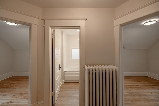 hall with baseboards, light wood-style flooring, and radiator