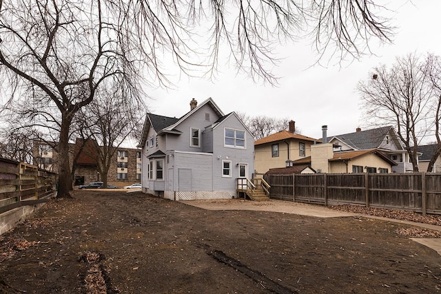 back of property featuring fence private yard, a residential view, and a chimney