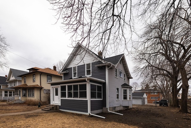 back of property featuring entry steps, a chimney, and a sunroom