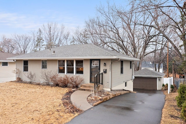 ranch-style home with roof with shingles, a detached garage, fence, and an outdoor structure