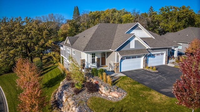 view of front of home featuring aphalt driveway, stone siding, roof with shingles, and a garage