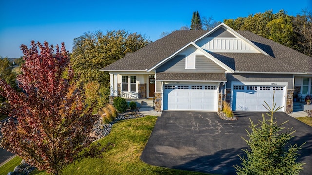 view of front facade with a shingled roof, stone siding, driveway, and an attached garage