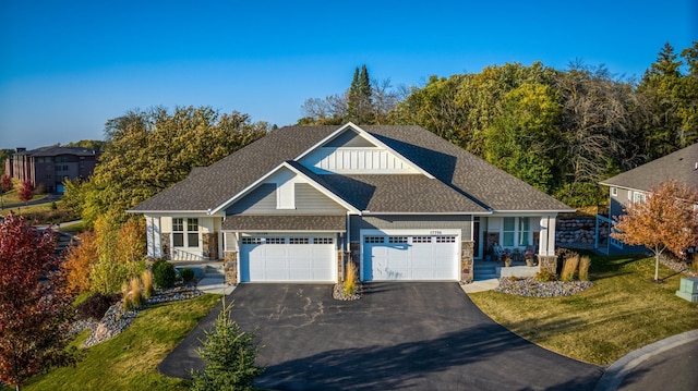 view of front facade featuring a garage, a shingled roof, driveway, stone siding, and a front lawn