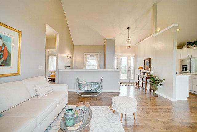 living room featuring vaulted ceiling, light wood-style flooring, and baseboards