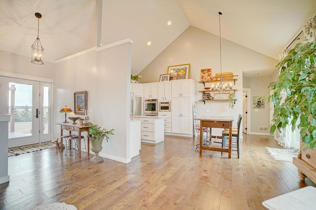 kitchen featuring light wood-style flooring, stainless steel appliances, light countertops, white cabinetry, and a notable chandelier