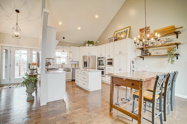 kitchen featuring light wood-type flooring, an inviting chandelier, stainless steel appliances, and light countertops