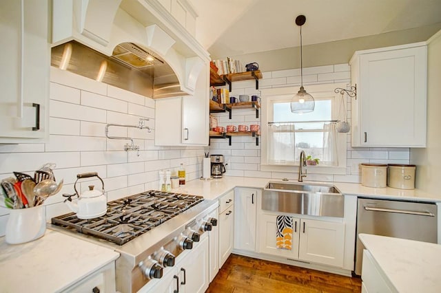 kitchen featuring premium range hood, a sink, white cabinets, appliances with stainless steel finishes, and backsplash